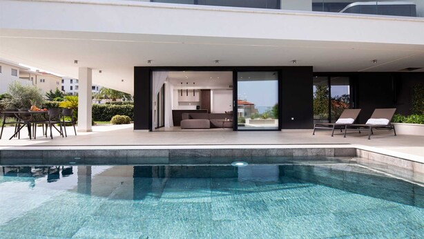 A modern outdoor pool area with a clear pool, lounge chairs, and a seating area with a sofa and table. - Villas Azimut – Superior Apartment with Pool, Terrace and Stunning Sea View (Malinska (Krk))