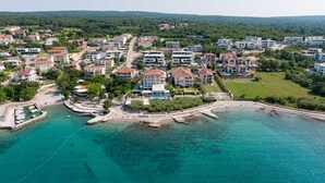 An aerial view of a coastal residential area with modern buildings, a marina, and a beach. - Villas Azimut – Superior Apartment with Pool, Terrace and Stunning Sea View (Malinska (Krk))