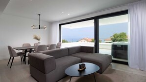 Ein modernes Wohnzimmer mit einem Ecksofa, einem runden Couchtisch und einem Essbereich mit Tisch und Stühlen.