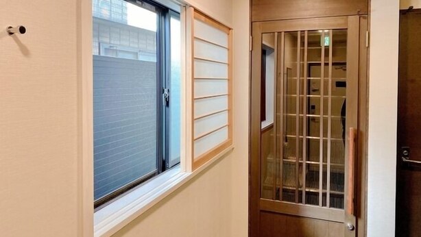 Un pasillo con una puerta corredera de vidrio y una puerta de madera con un panel de cristal.