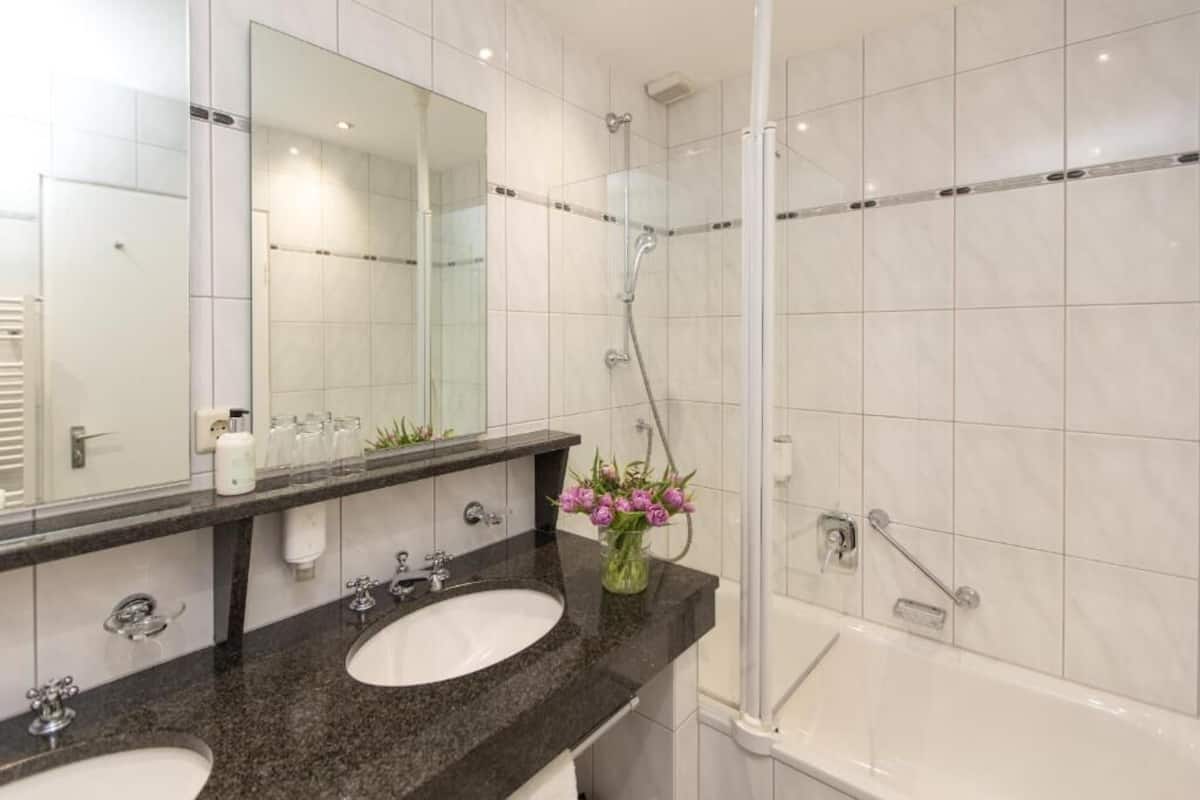 Ein modernes Badezimmer mit zwei Waschbecken, einem großen Spiegel und einer Duschkabine.