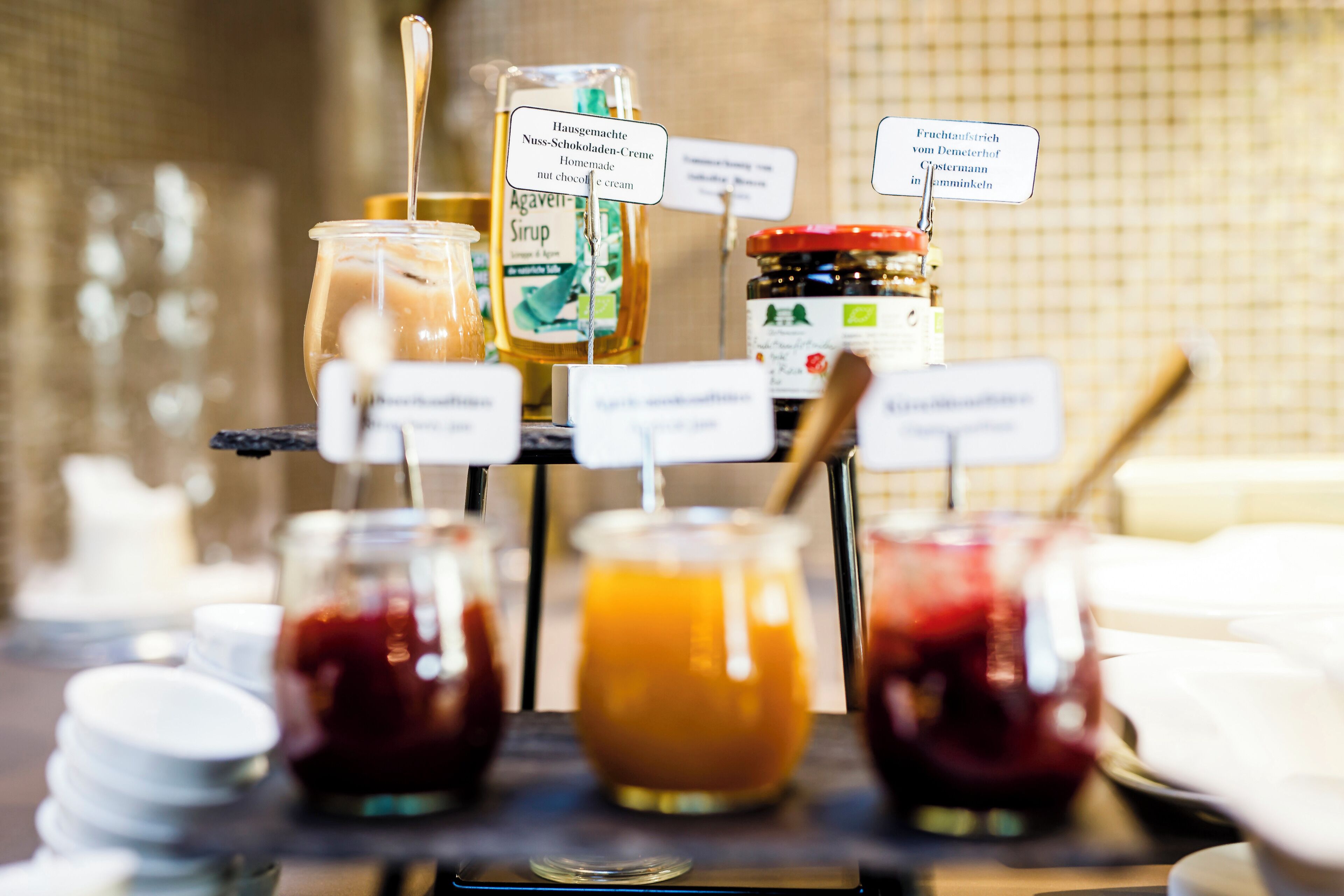 Buffet com diversos alimentos e acompanhamentos, incluindo potes de molhos e uma garrafa de xarope.