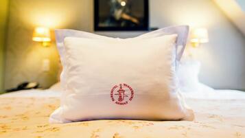 A hotel room with a bed, a pillow with a logo, and two wall-mounted lamps.