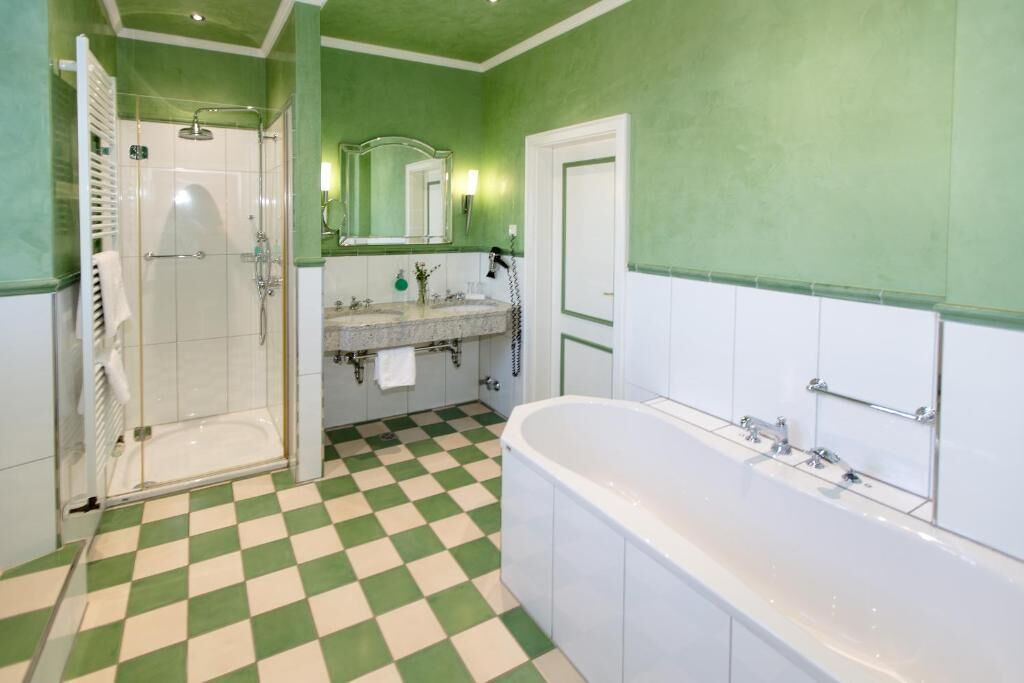 A bathroom with a checkered floor, a shower, a sink, and a bathtub.