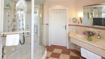 A modern bathroom with a glass-enclosed shower, a separate bathtub, and a vanity with a mirror.