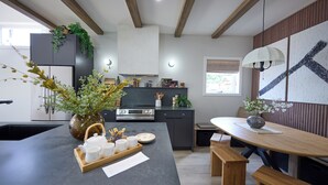 Cozinha moderna com ilha central, vigas de madeira e área de jantar com bancos.