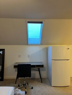 A small room with a desk, a chair, a refrigerator, and a skylight. - Serene Mountain‑View Retreat in a Quiet, Well‑Located Neighborhood (Abbotsford)