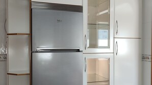 A kitchen with a built-in refrigerator, white cabinets, and a glass door cabinet. - Pensión Armonía (Caldas de Reis)