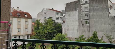 Un balcón con barandilla de hierro forjado, un farol colgante y vistas de edificios residenciales al fondo.