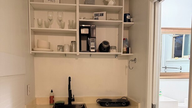 A small kitchen with white cabinets, a coffee maker, and a sink.