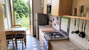 A modern kitchen with wooden cabinets, a gas stove, a refrigerator, and a window overlooking greenery. - Giannotti Vintage Apartment With Two Bedrooms (Firenze)