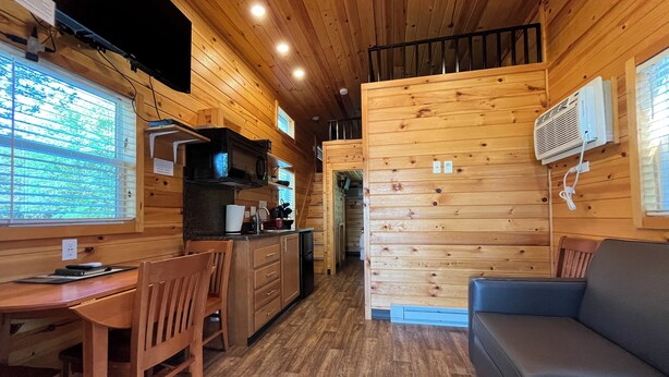 Een houten chalet inrichting met een keuken, eethoek en een bank.