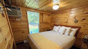 Een houten slaapkamer met een bed, een heater en een raam.