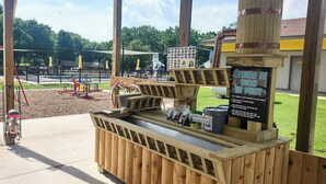 Een houten kiosk met een bord waarop staat 'STRIKE IT IN FUN!' en een etalage voor de verkoop van artikelen.