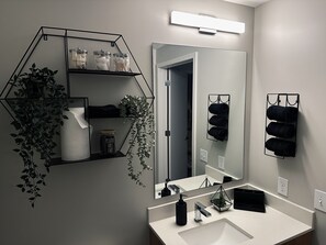 A modern bathroom with a geometric shelf unit, a mirror, and a towel rack. - Luxury High Rise • Rooftop Pool (Atlanta)