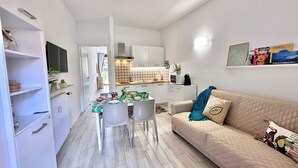 Eine moderne Wohnung mit Essbereich, einer Küchenzeile und einem Wohnzimmer mit Sofa und Zierkissen.