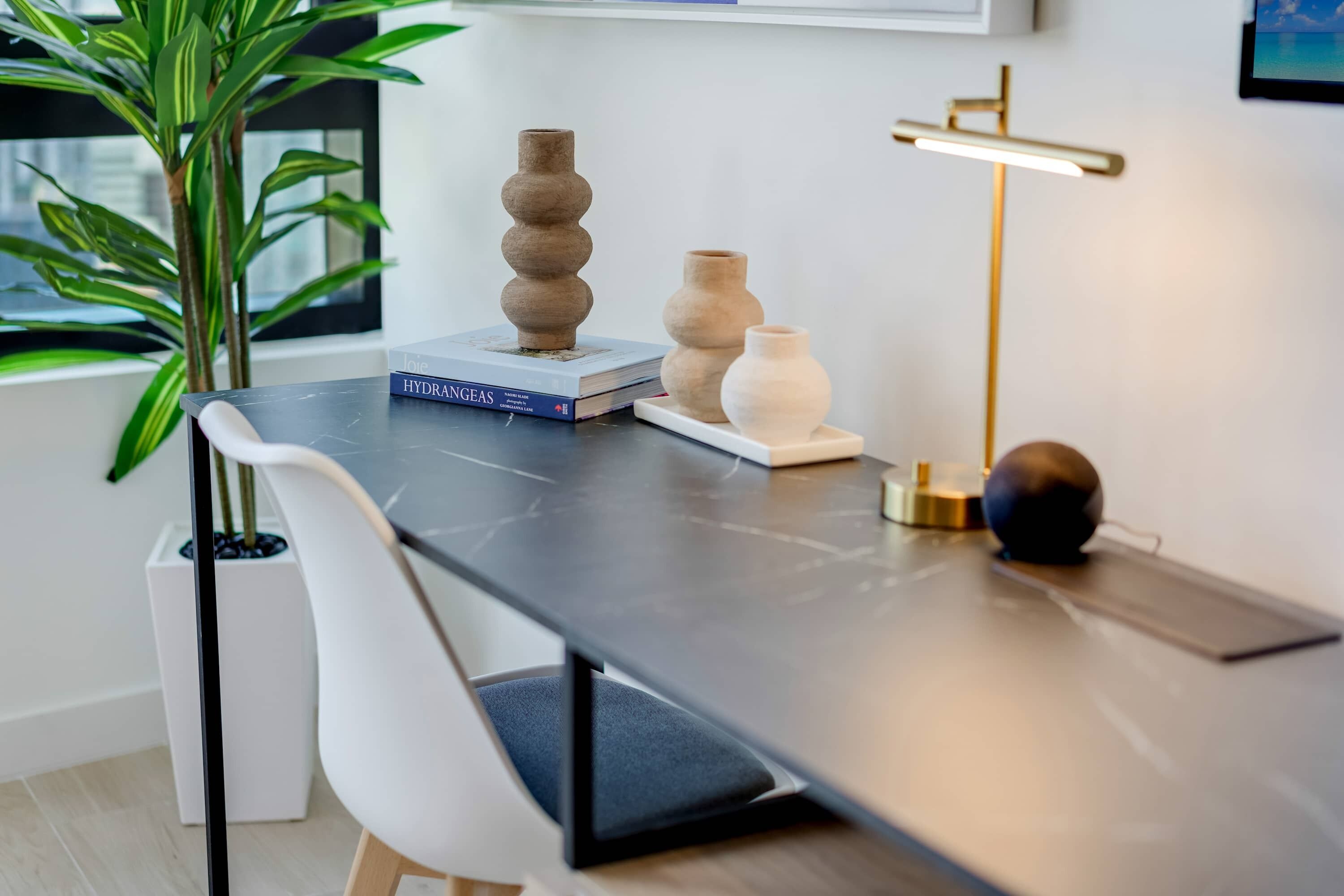 A modern desk with a book titled "HYDRANGEAS" and two ceramic vases.