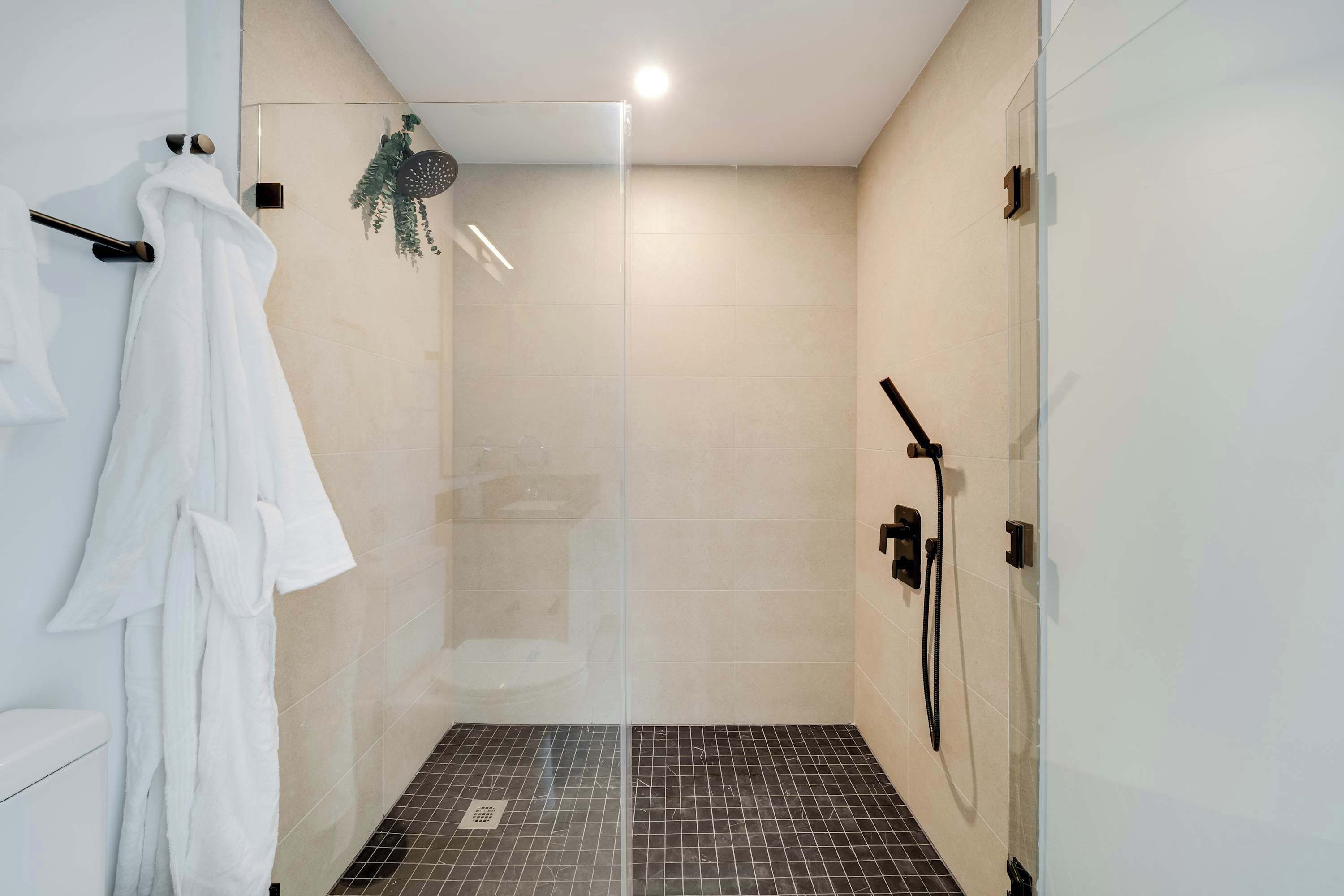 A modern bathroom with a glass-enclosed shower, a white towel rack, and a visible showerhead.