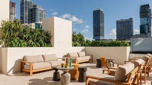 A rooftop terrace with outdoor seating, including sofas and chairs, and a view of surrounding high-rise buildings. - Sky Corner Residence- Pool, Parking, Amenities (Miami)