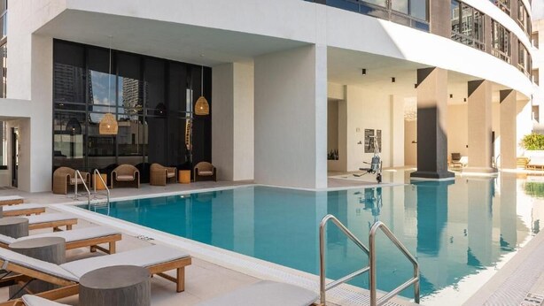 A modern hotel with a large indoor swimming pool, lounge area with sun loungers, and a contemporary architectural design. - Sky Corner Residence- Pool, Parking, Amenities (Miami)