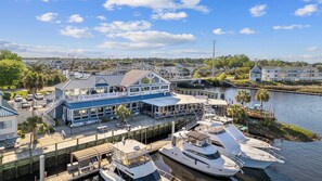 A waterfront property with a docked boat, a building labeled 'Freedom Boat Club,' and a view of the surrounding neighborhood. - Waterway Marina Views, 3BR Balcony, Harborgate (North Myrtle Beach)
