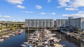 A marina with boats docked, a bridge, and a multi-story hotel with balconies. - Waterway Marina Views, 3BR Balcony, Harborgate (North Myrtle Beach)