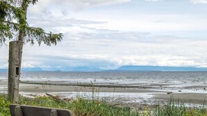 A bench overlooking a beach with a view of the sea and distant mountains. - Beachfront 2 bed | Arcade, A+ Views, Lux King bed (Strathcona D (Oyster Bay-Bu*)