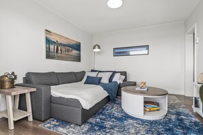 A modern living room with a grey sectional sofa, a round coffee table, and a blue patterned rug.