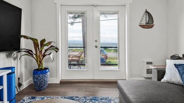 A modern living room with a large sliding glass door leading to a balcony with a view of the ocean. - Beachfront 2 bed | Arcade, A+ Views, Lux King bed (Strathcona D (Oyster Bay-Bu*)