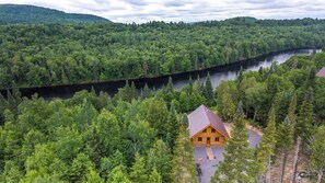 A cabin surrounded by dense forest and a river.