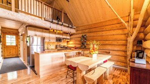 A log cabin interior with a kitchen, dining area, and a loft space. - Uniquely landscaped log cabin with spa! (Lac-aux-Sables)