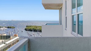 Vista de un puerto deportivo con numerosos barcos, cielo despejado y un edificio blanco con grandes ventanales.