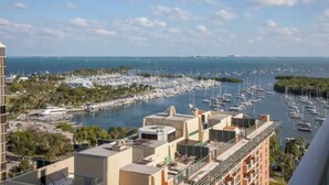 Una marina con numerosos barcos, cielo despejado y edificios en primer plano.