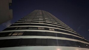 Een hoog, modern gebouw met een gebogen gevel en veel ramen.