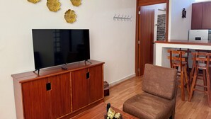 A modern living room with a flat-screen TV, wooden furniture, and decorative wall art.