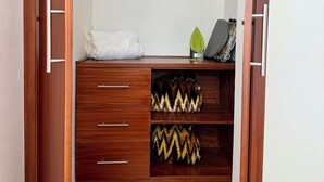 A wooden closet with a mirror, a towel, and a shelf with patterned cushions.