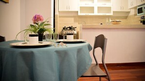 A dining area with a table set for two, a vase with flowers, and a stove in the background. - 1 bedroom comfort apartment in Cusco (Cusco)