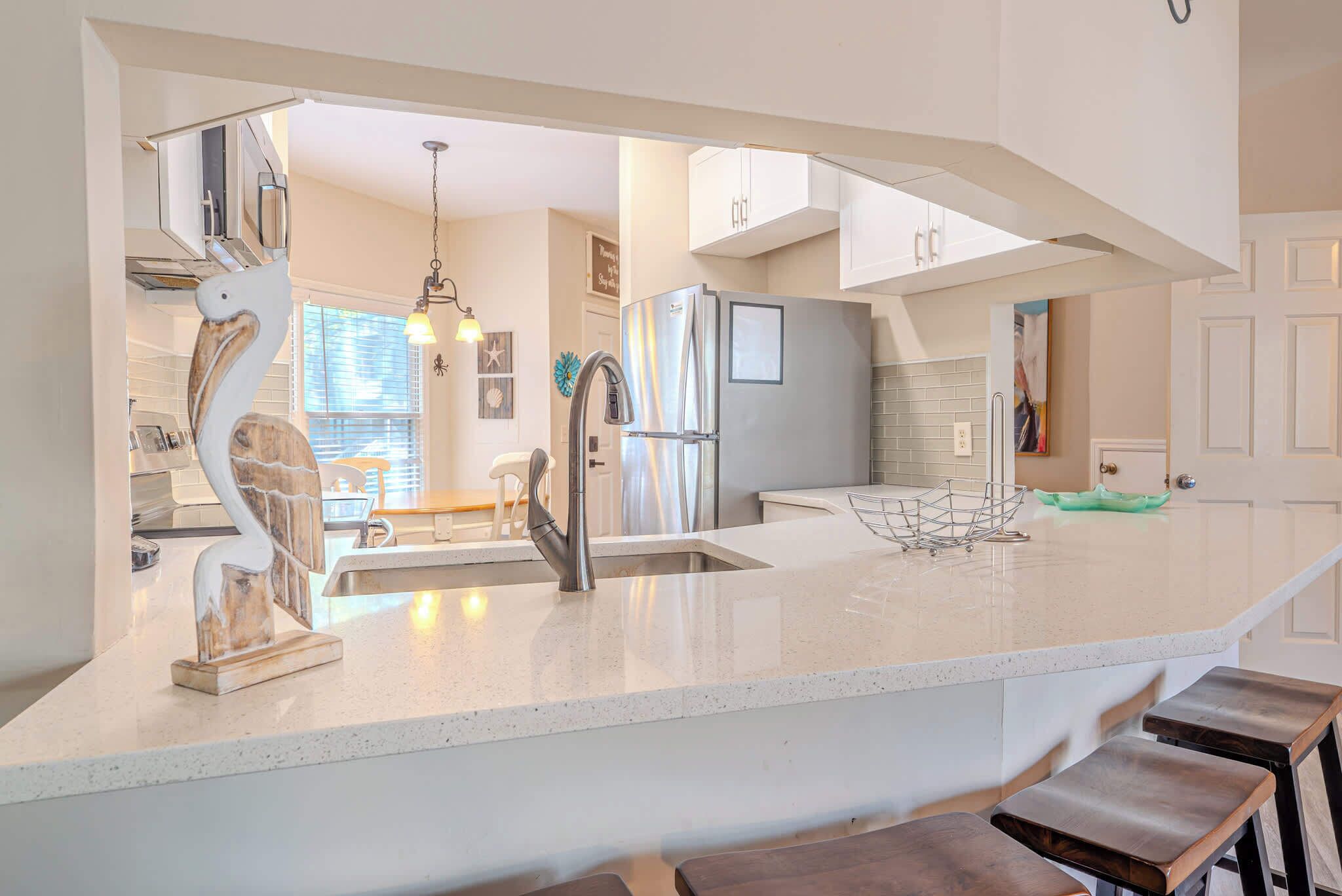 A modern kitchen with a large island, stainless steel appliances, and a unique sculptural chair.