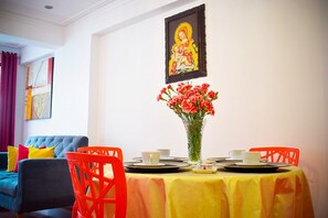 A dining area with a table set for two, a vase of flowers, and a framed religious painting on the wall. - Comfortable 2-bedroom apartment in Cusco (Cusco)
