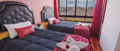 A hotel room with two beds, a large window with a mountain view, and a brick-patterned wall.