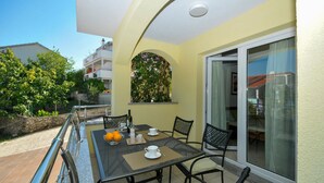 An outdoor patio with a table set for two, chairs, and a view of a building in the background. - Awesome apartment in Okrug Gornji with WiFi (Okrug Gornji)