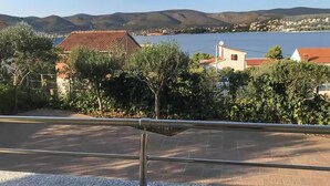 Une vue côtière avec un bâtiment doté d’un toit rouge, une étendue d’eau et des collines en arrière-plan.