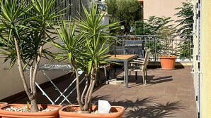 Un espace extérieur aménagé en terrasse, avec des jardinières en terre cuite, une table, des chaises et un barbecue.