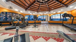 Ein Fitnessstudio mit unterschiedlichen Trainingsgeräten, großen Fenstern und Blick auf die Stadt.