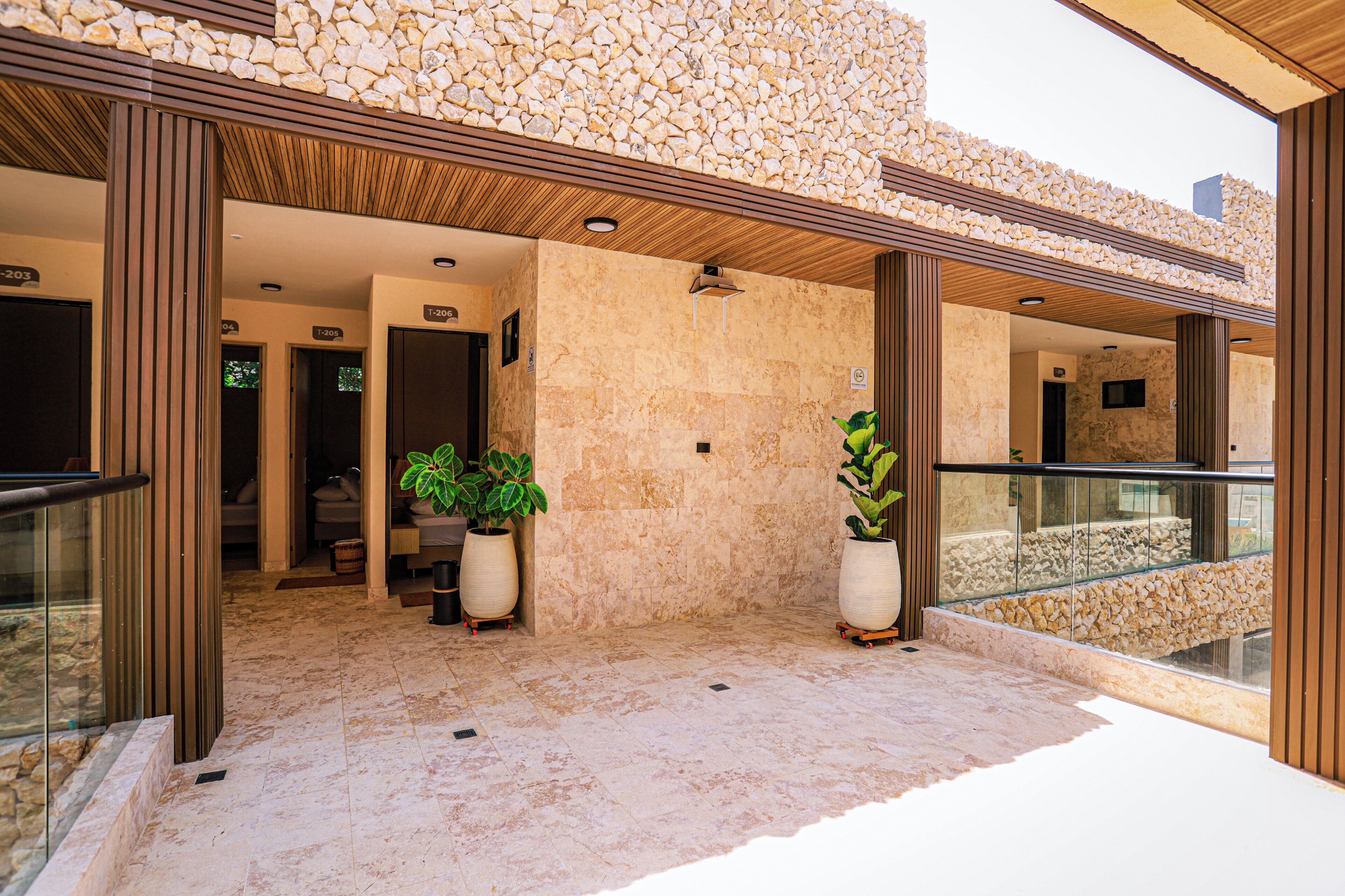 A hotel lobby with a stone wall, potted plants, and a glass railing.