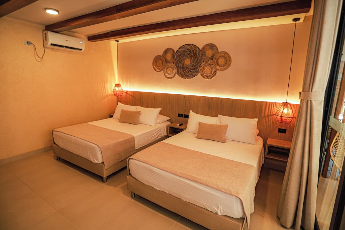 Habitación de hotel con dos camas, aire acondicionado de pared y un adorno mural.