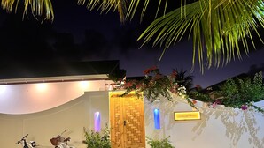 A building entrance with a wooden door, two bicycles parked outside, and a sign reading "HANDHUVARU MALDIVES". - Handhuvaru Maldives (Milandhoo)