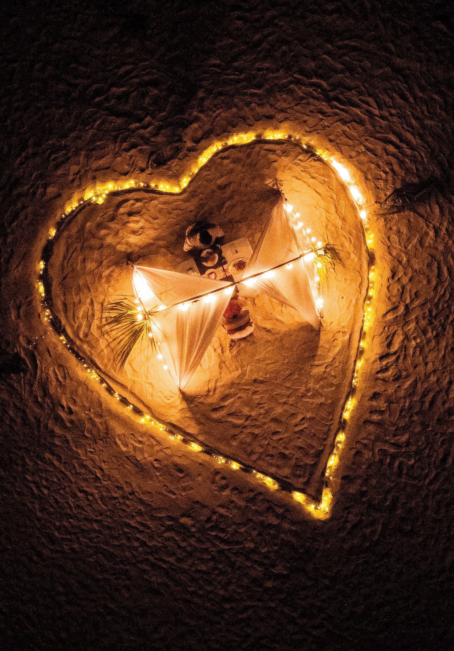 A heart-shaped cave illuminated by string lights, with a person inside.