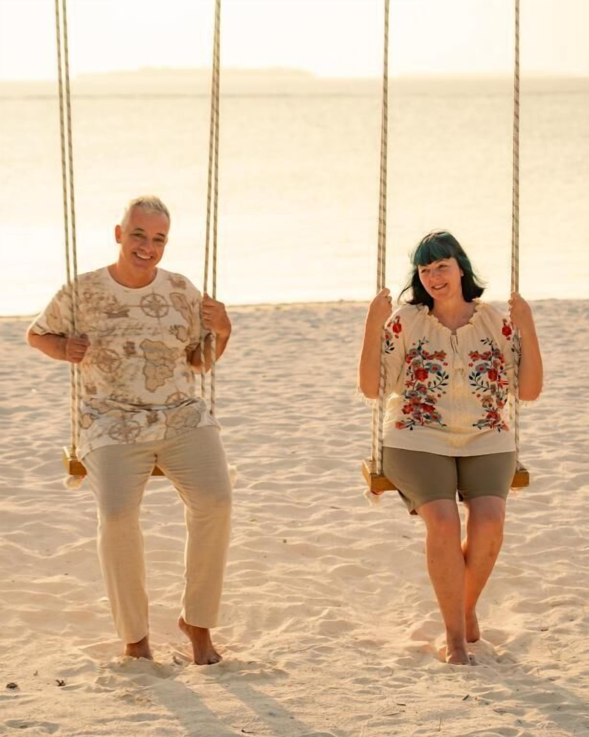 Dos personas en un columpio en la playa.