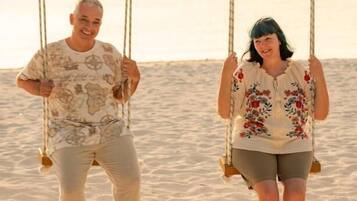 Dos personas en un columpio en la playa.
